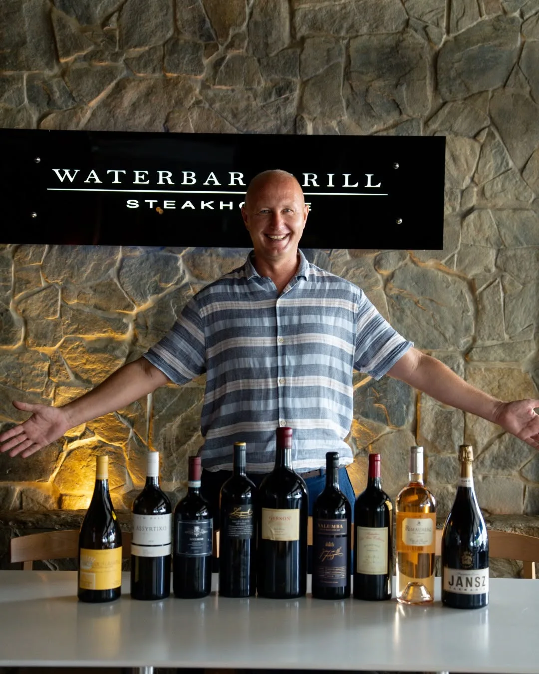 Owner welcoming guests beside a lineup of wines at Waterbar & Grill Steakhouse, Cairns