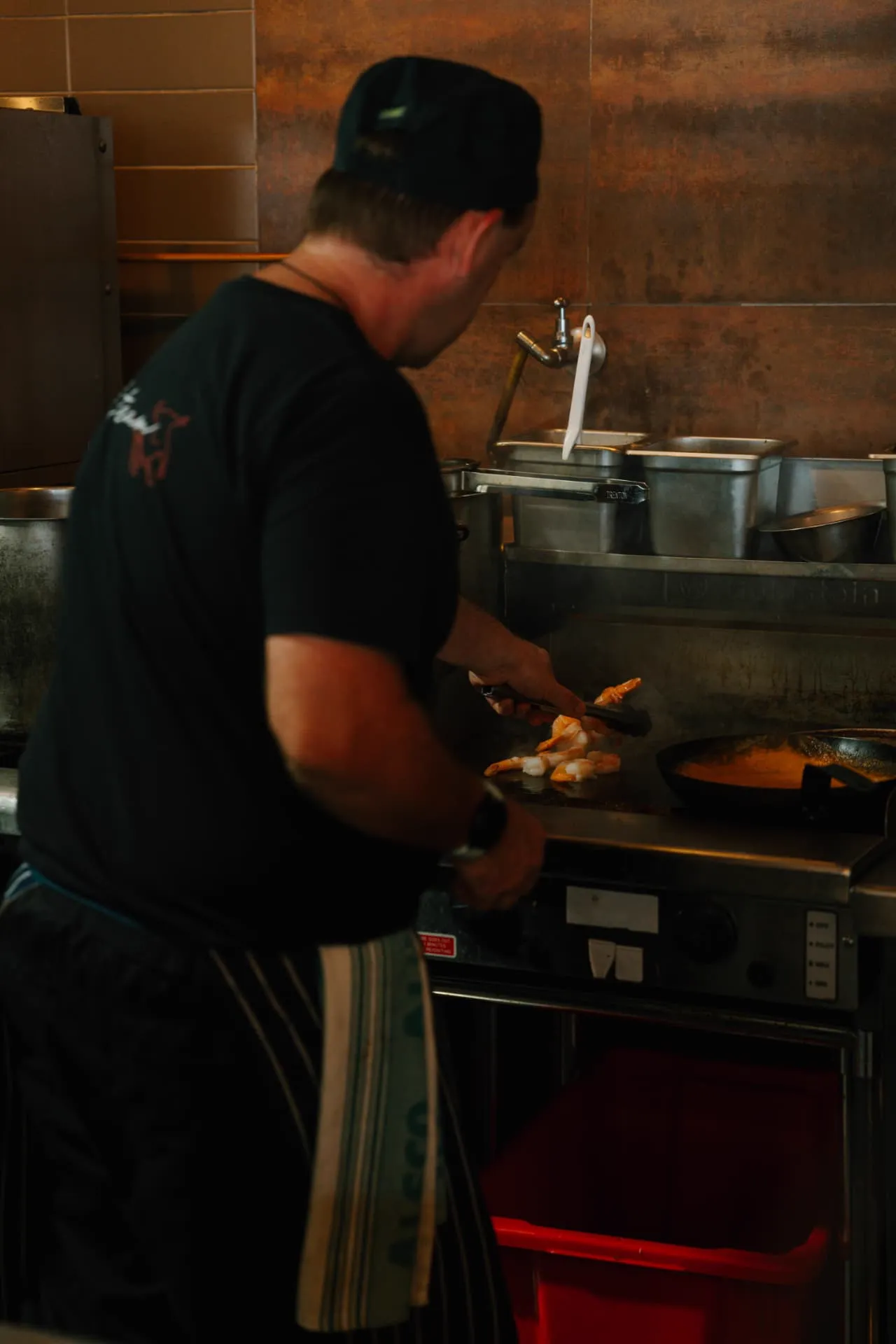 Chef searing prawns on the grill in the kitchen at Waterbar & Grill Steakhouse, Cairns